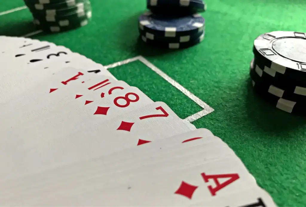 Vista em close-up de cartas de pôquer e fichas em uma mesa de feltro verde, perfeita para conteúdo com tema de cassino.