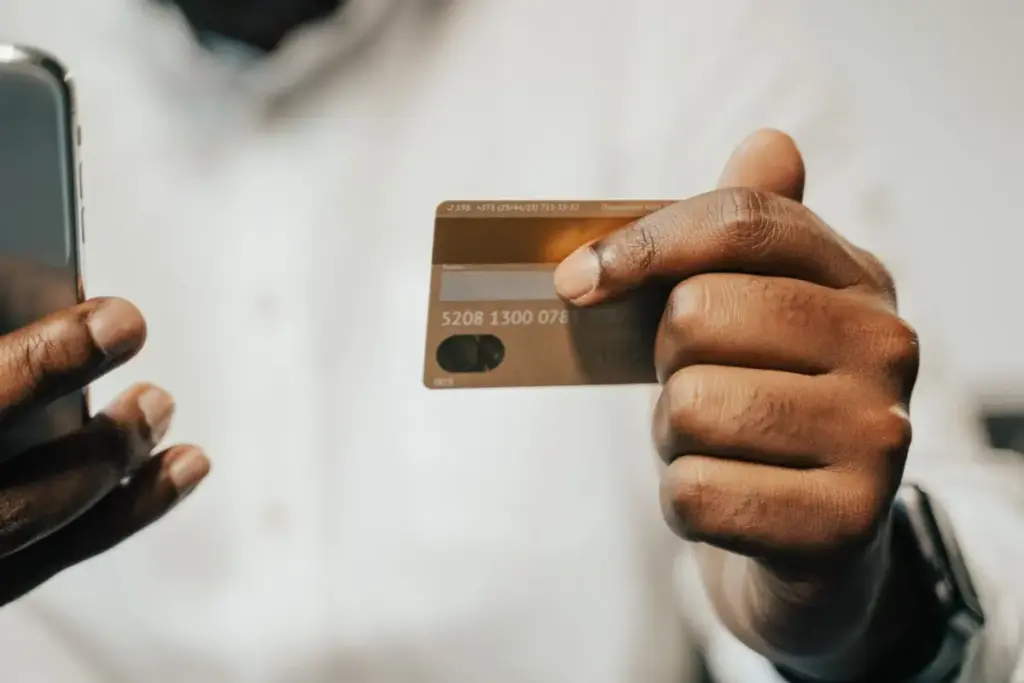 Pessoa usando um smartphone e cartão de crédito para compras online ou pagamento.