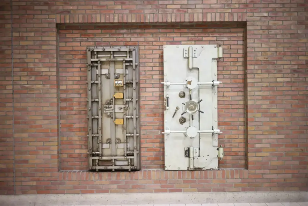 Duas portas de cofre de aço fixadas a uma parede de tijolos vintage, mostrando resistência industrial.