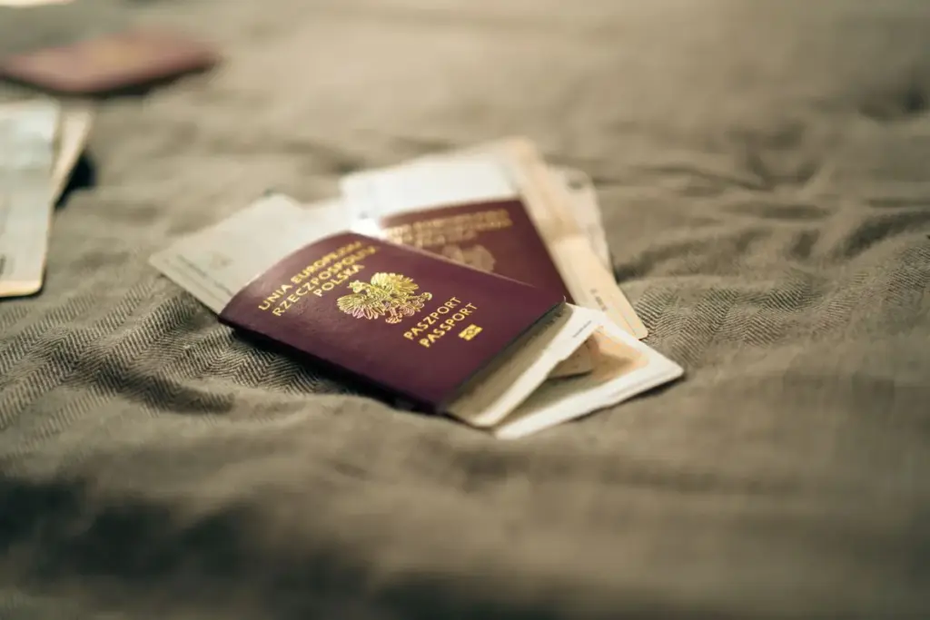 Close-up de um passaporte polonês e documentos de viagem colocados sobre uma superfície de tecido, simbolizando viagem e identidade.