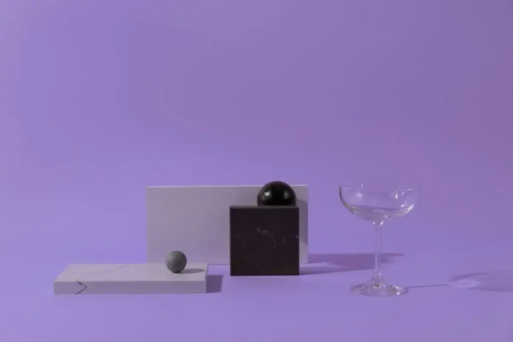 Composição minimalista abstrata de formas geométricas e um copo, sobre um fundo pastel.