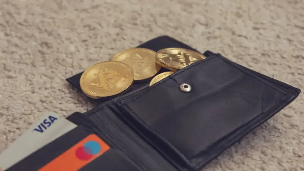 Close-up de bitcoins e cartões de crédito dentro de uma carteira de couro, representando moeda digital e finanças.
