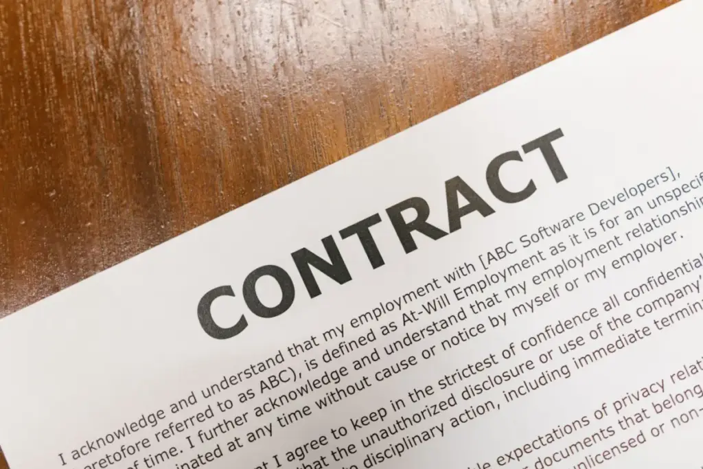 Um close detalhado de um documento de contrato impresso sobre a superfície de uma mesa de madeira.